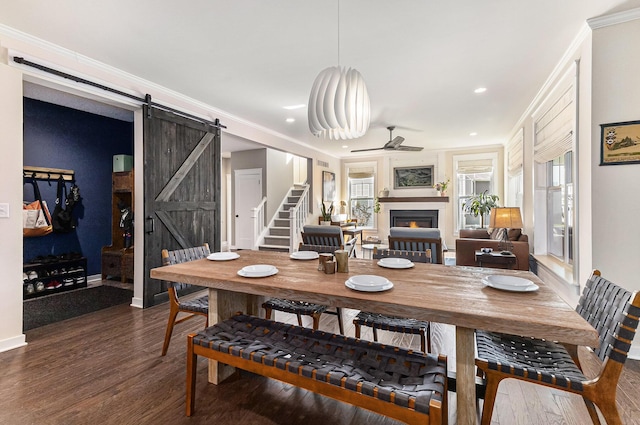 6217 S Trailwoods Dr, Ann Arbor, MI 48103 - dining space featuring a barn door, a ceiling fan, dark wood-type flooring, recessed lighting, and crown molding