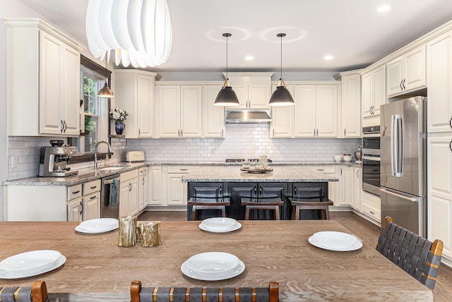 6217 S Trailwoods Dr, Ann Arbor, MI 48103 - kitchen with stainless steel appliances, under cabinet range hood, tasteful backsplash, pendant lighting, and recessed lighting