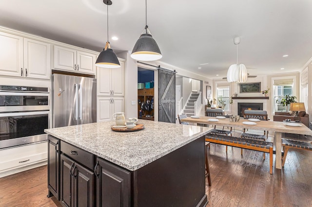 6217 S Trailwoods Dr, Ann Arbor, MI 48103 - kitchen featuring a barn door, stainless steel appliances, open floor plan, white cabinets, and dark wood-style floors