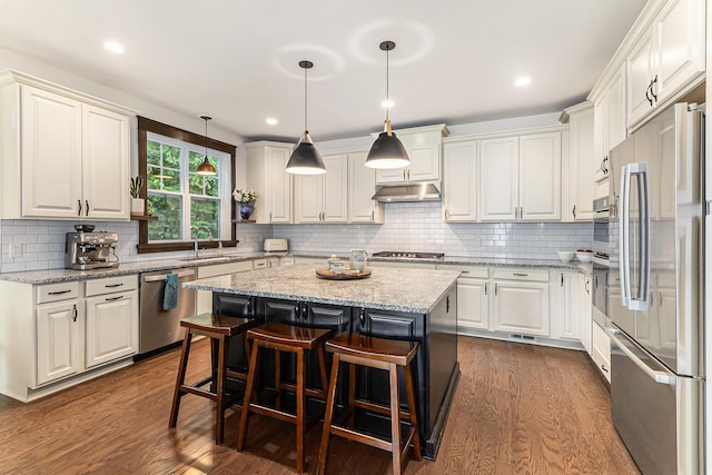 6217 S Trailwoods Dr, Ann Arbor, MI 48103 - kitchen with appliances with stainless steel finishes, under cabinet range hood, dark wood-type flooring, white cabinets, and a kitchen island