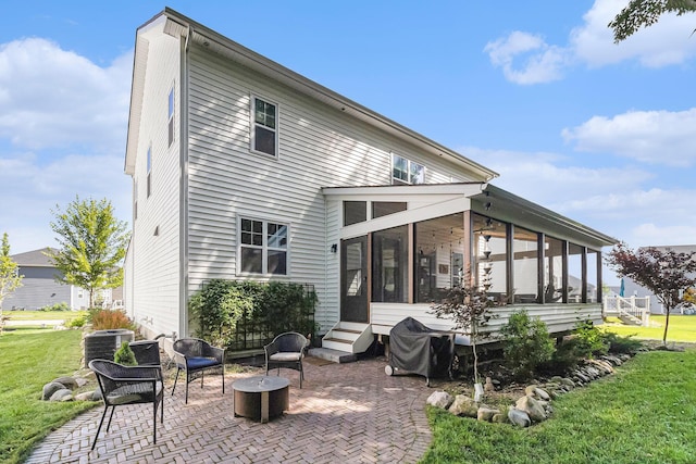 6217 S Trailwoods Dr, Ann Arbor, MI 48103 - back of property featuring a sunroom, a patio area, a lawn, and a fire pit