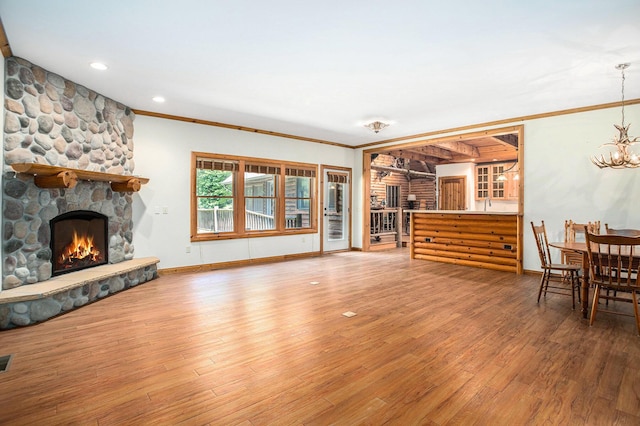 11463 Snowshoe Dr, Plainwell, MI 49080 - living area featuring a stone fireplace, a chandelier, wood finished floors, ornamental molding, and recessed lighting
