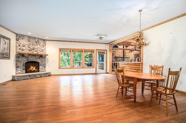 11463 Snowshoe Dr, Plainwell, MI 49080 - dining room with wood finished floors, a fireplace, ornamental molding, and a chandelier