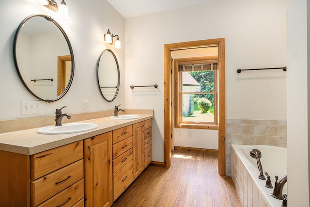 11463 Snowshoe Dr, Plainwell, MI 49080 - full bathroom featuring double vanity, a relaxing tiled tub, and wood finished floors