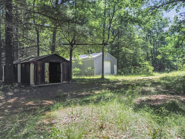 2267 Caberfae Hwy, Manistee, MI 49660 - view of yard with a detached garage, a view of trees, and a storage unit