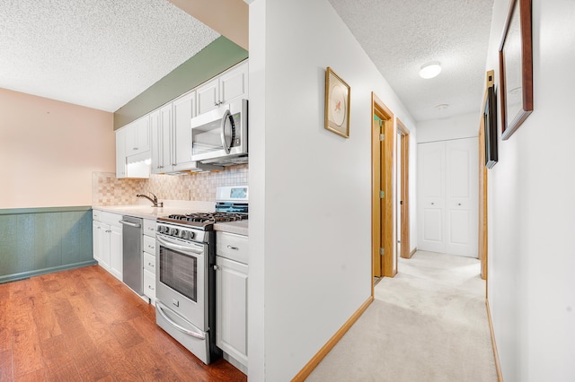18165 Shamrock Blvd, Big Rapids, MI 49307 - kitchen featuring appliances with stainless steel finishes, a textured ceiling, white cabinets, light countertops, and backsplash