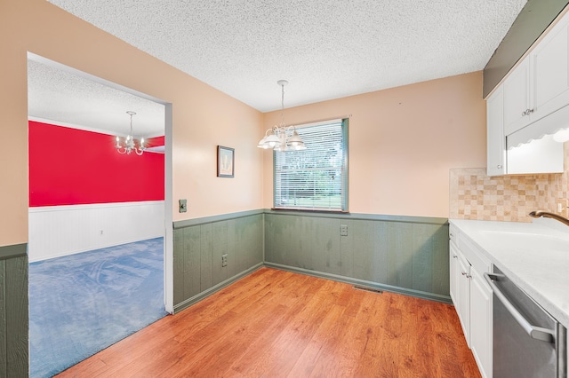 18165 Shamrock Blvd, Big Rapids, MI 49307 - unfurnished dining area with a chandelier, wainscoting, a textured ceiling, and light wood-style floors