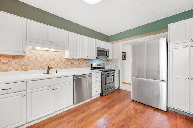 18165 Shamrock Blvd, Big Rapids, MI 49307 - kitchen featuring appliances with stainless steel finishes, light wood finished floors, white cabinetry, light countertops, and backsplash