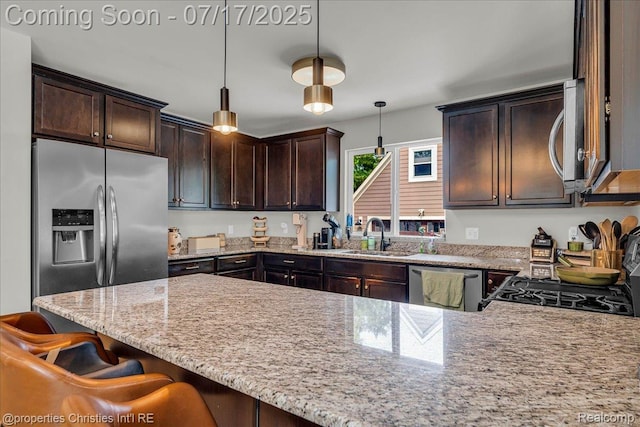 1305 Wyandotte Ave, Royal Oak, MI 48067 - kitchen with appliances with stainless steel finishes, dark brown cabinets, a peninsula, light stone countertops, and decorative light fixtures