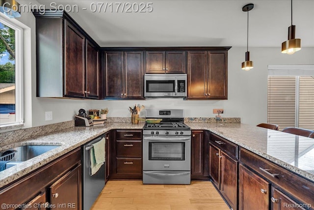 1305 Wyandotte Ave, Royal Oak, MI 48067 - kitchen with stainless steel appliances, light stone countertops, light wood-style flooring, dark brown cabinets, and hanging light fixtures