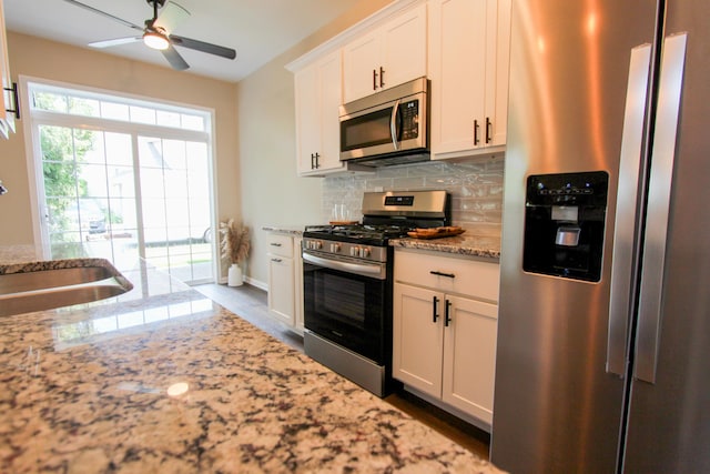 3216 E Morgan Creek Ct, Indiana, IN 46385 - kitchen with appliances with stainless steel finishes, light stone counters, tasteful backsplash, white cabinets, and a ceiling fan
