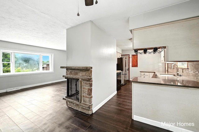 1435 Sweet St NE, Grand Rapids, MI 49505 - unfurnished living room with a stone fireplace, dark wood-type flooring, and a ceiling fan