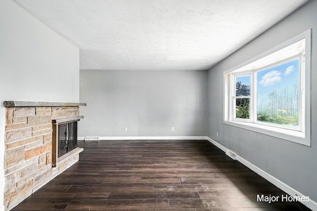 1435 Sweet St NE, Grand Rapids, MI 49505 - unfurnished living room featuring a stone fireplace, wood finished floors, and a textured ceiling