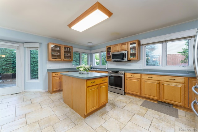 13381 Latheron Dr, Plymouth, MI 48170 - kitchen featuring stainless steel appliances, ornamental molding, glass insert cabinets, a center island, and stone tile floors