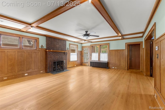 830 S Brady Rd, Dearborn, MI 48124 - unfurnished living room featuring radiator, a wainscoted wall, beamed ceiling, light wood-style floors, and a brick fireplace