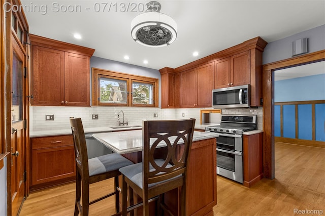 830 S Brady Rd, Dearborn, MI 48124 - kitchen with stainless steel appliances, backsplash, light wood-type flooring, a kitchen island, and recessed lighting