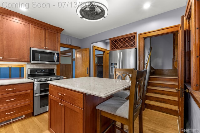 830 S Brady Rd, Dearborn, MI 48124 - kitchen with stainless steel appliances, light wood-type flooring, a breakfast bar, a center island, and light stone counters