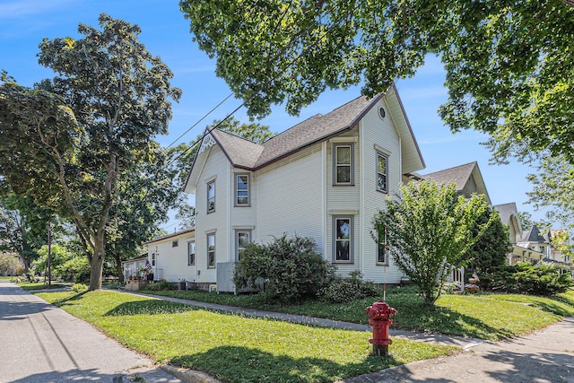 449 4th St, Manistee, MI 49660 - view of property exterior featuring a lawn and a shingled roof