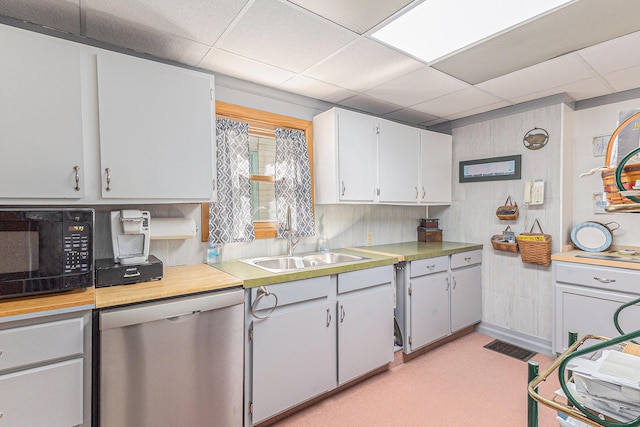 449 4th St, Manistee, MI 49660 - kitchen with dishwasher, black microwave, light countertops, a drop ceiling, and light carpet