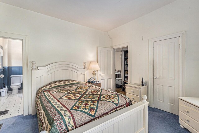 449 4th St, Manistee, MI 49660 - bedroom with dark carpet, connected bathroom, and a wainscoted wall