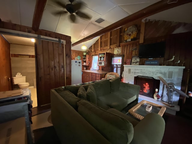 2031 E Oak St, Newaygo, MI 49337 - living room featuring wood walls, a ceiling fan, a barn door, lofted ceiling, and a fireplace