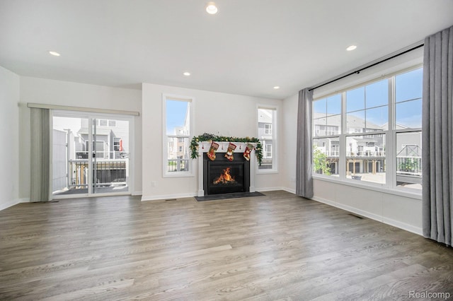 2965 Aughton Rd, Ann Arbor, MI 48105 - unfurnished living room featuring healthy amount of natural light, wood finished floors, a warm lit fireplace, and recessed lighting