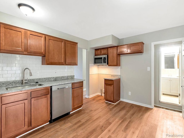 33855 Cherry Hill Rd, Westland, MI 48186 - kitchen featuring stainless steel appliances, brown cabinetry, light stone counters, decorative backsplash, and light wood finished floors