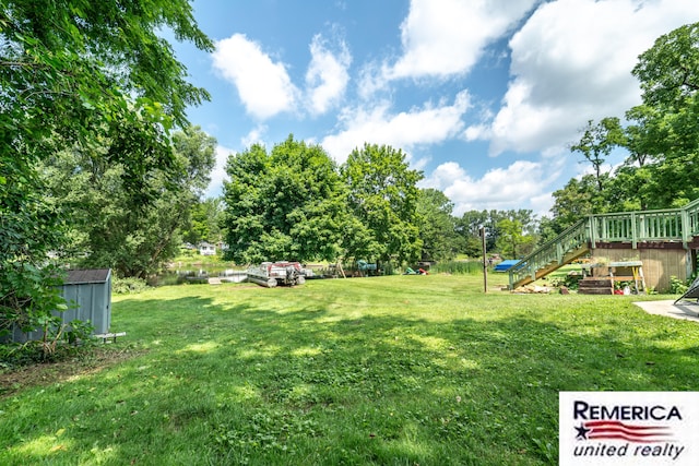 9420 Van Antwerp Rd, Brighton, MI 48116 - view of grassy yard with stairway, a storage unit, and a deck