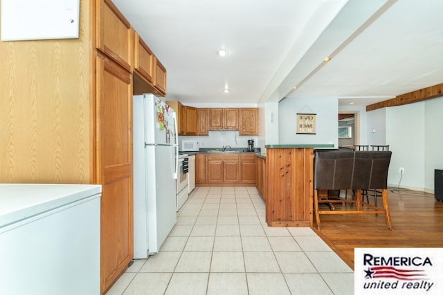 9420 Van Antwerp Rd, Brighton, MI 48116 - kitchen with white appliances, a peninsula, brown cabinetry, light tile patterned floors, and recessed lighting