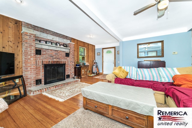 9420 Van Antwerp Rd, Brighton, MI 48116 - living area featuring wood finished floors, ceiling fan, wood walls, and a brick fireplace