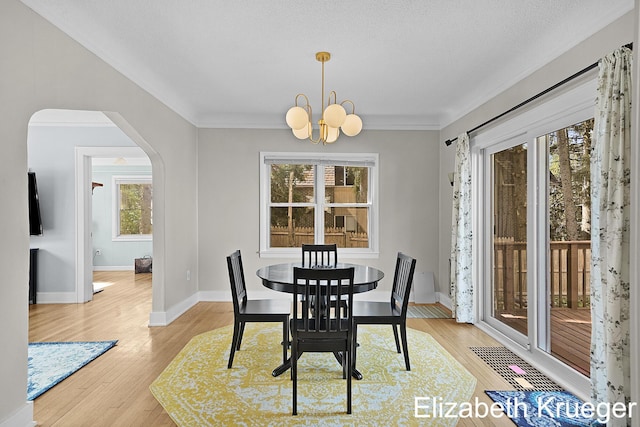 1215 Emerald Ave NE, Grand Rapids, MI 49505 - dining space with arched walkways, a chandelier, light wood-style flooring, and ornamental molding