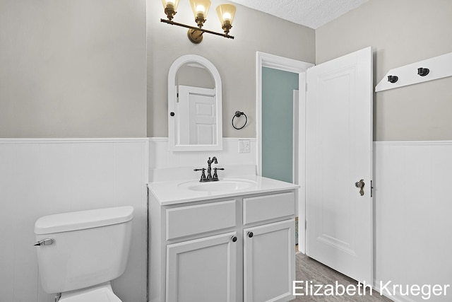 1215 Emerald Ave NE, Grand Rapids, MI 49505 - bathroom featuring wainscoting, vanity, wood finished floors, and a textured ceiling