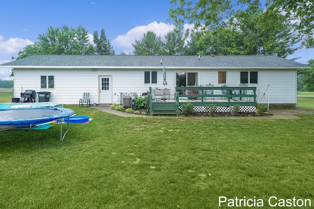 4707 Cannonsburg Rd NE, Belmont, MI 49306 - back of property featuring a deck, a trampoline, and a yard
