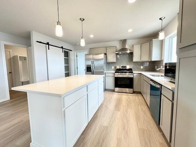 LOT100 Wren Dr SE, Caledonia, MI 49316 - kitchen with appliances with stainless steel finishes, wall chimney exhaust hood, light wood-type flooring, a barn door, and light countertops