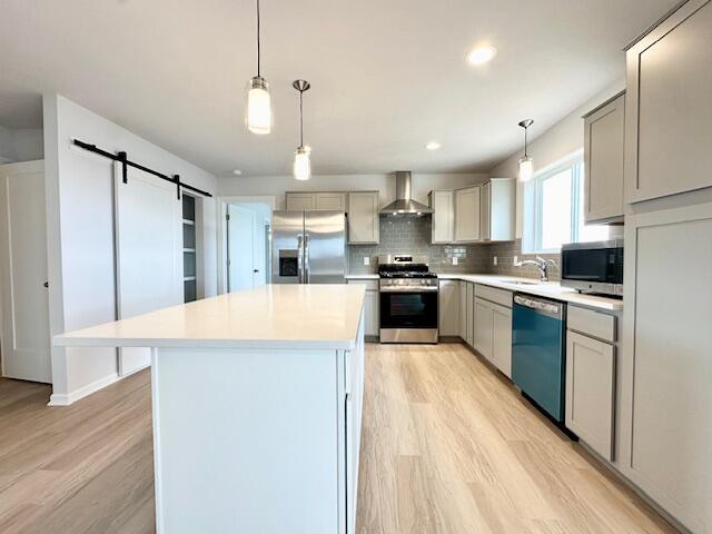 LOT100 Wren Dr SE, Caledonia, MI 49316 - kitchen with stainless steel appliances, wall chimney exhaust hood, light wood-type flooring, a barn door, and light countertops