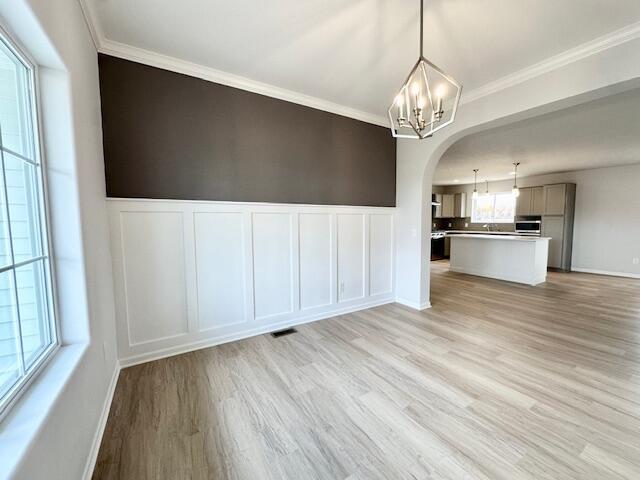 LOT100 Wren Dr SE, Caledonia, MI 49316 - unfurnished dining area with a chandelier, a decorative wall, arched walkways, light wood-style flooring, and ornamental molding