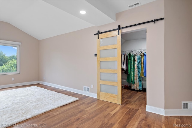 6727 Napier Rd, Plymouth, MI 48170 - unfurnished bedroom with a barn door, a walk in closet, wood finished floors, lofted ceiling, and recessed lighting