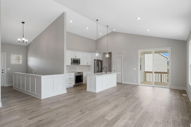 6153 Lake Wind Ave, Holland, MI 49423 - kitchen with appliances with stainless steel finishes, light wood-style flooring, high vaulted ceiling, open floor plan, and a kitchen island with sink