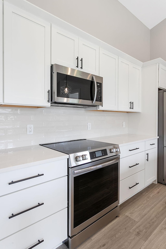 6153 Lake Wind Ave, Holland, MI 49423 - kitchen featuring stainless steel appliances, light wood-style floors, tasteful backsplash, white cabinetry, and light countertops