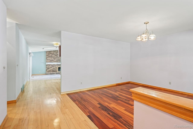 609 N Wickshire Ln, Durand, MI 48429 - spare room with a chandelier, light wood-type flooring, and a fireplace