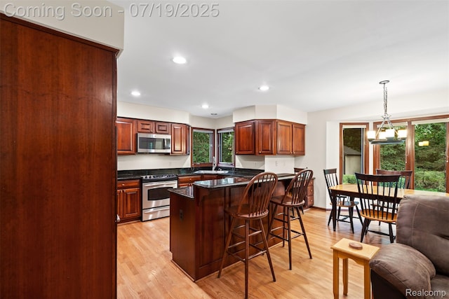 260 Forest Crest Dr, Commerce Twp, MI 48390 - kitchen with stainless steel appliances, a breakfast bar area, light wood-style floors, pendant lighting, and a chandelier
