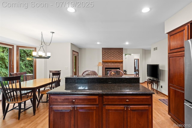 260 Forest Crest Dr, Commerce Twp, MI 48390 - kitchen featuring light wood-type flooring, a fireplace, hanging light fixtures, dark stone counters, and recessed lighting