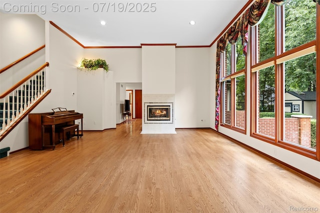 260 Forest Crest Dr, Commerce Twp, MI 48390 - unfurnished living room featuring healthy amount of natural light, light wood-style floors, ornamental molding, stairs, and a fireplace