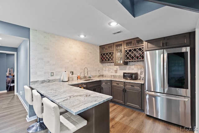 579 Budlong St, Adrian, MI 49221 - kitchen featuring smart refrigerator, light stone counters, glass insert cabinets, light wood-style floors, and a peninsula