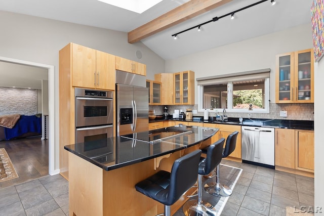 579 Budlong St, Adrian, MI 49221 - kitchen featuring appliances with stainless steel finishes, decorative backsplash, a kitchen breakfast bar, glass insert cabinets, and dark countertops
