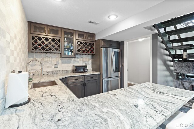 579 Budlong St, Adrian, MI 49221 - kitchen with smart refrigerator, light stone countertops, glass insert cabinets, backsplash, and black microwave