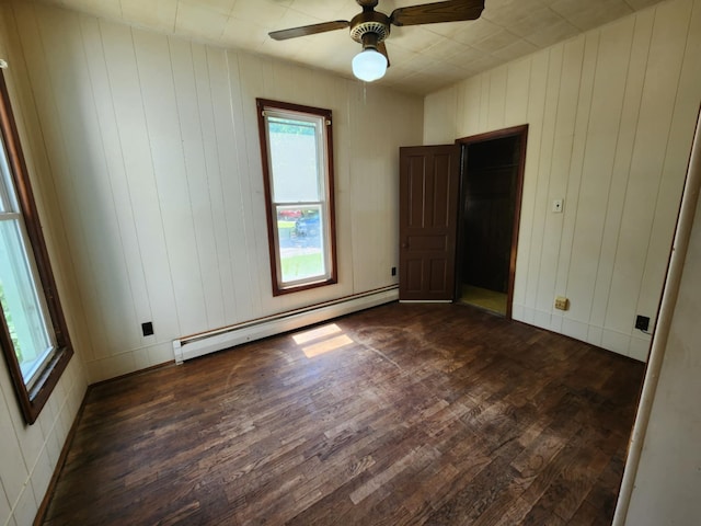 214 S Gorham St, Jackson, MI 49203 - unfurnished bedroom with baseboard heating, dark wood-style floors, ceiling fan, and wooden walls