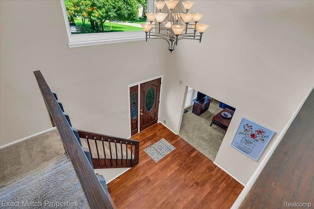 3742 Hearthstone Dr, Commerce Twp, MI 48382 - carpeted foyer entrance featuring a chandelier, stairway, wood finished floors, and a towering ceiling