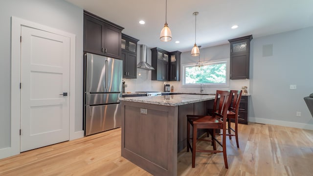 2816 Niles Buchanan Rd, Buchanan, MI 49107 - kitchen featuring stainless steel refrigerator, wall chimney exhaust hood, light wood-style flooring, a center island, and light stone counters