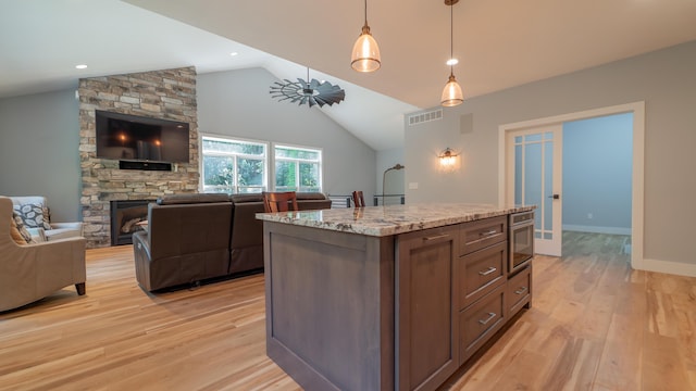 2816 Niles Buchanan Rd, Buchanan, MI 49107 - kitchen with stainless steel oven, open floor plan, light wood-type flooring, lofted ceiling, and decorative light fixtures